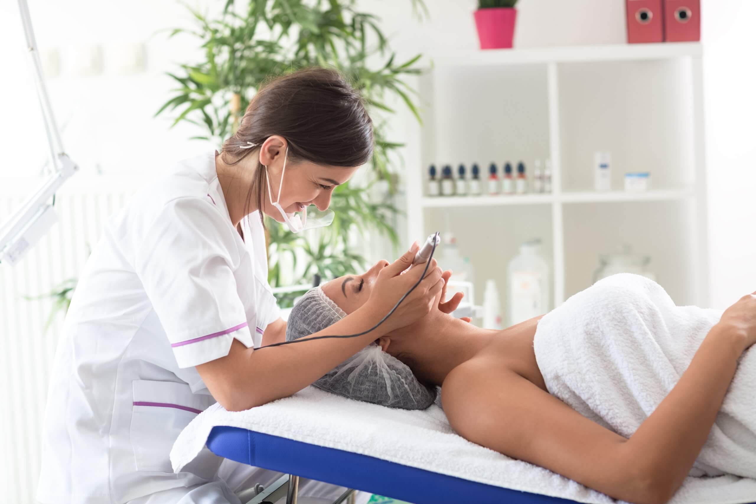 cosmetic laser technician performs laser aesthetic treatment on a client